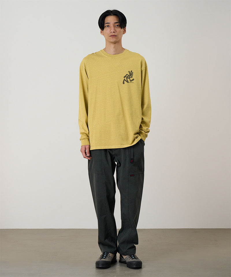 Model wearing a sulpher pigment Gramicci Running Man L/S Tee Pigment Dyed with a grey graphic and dark pants on a light-tone background.