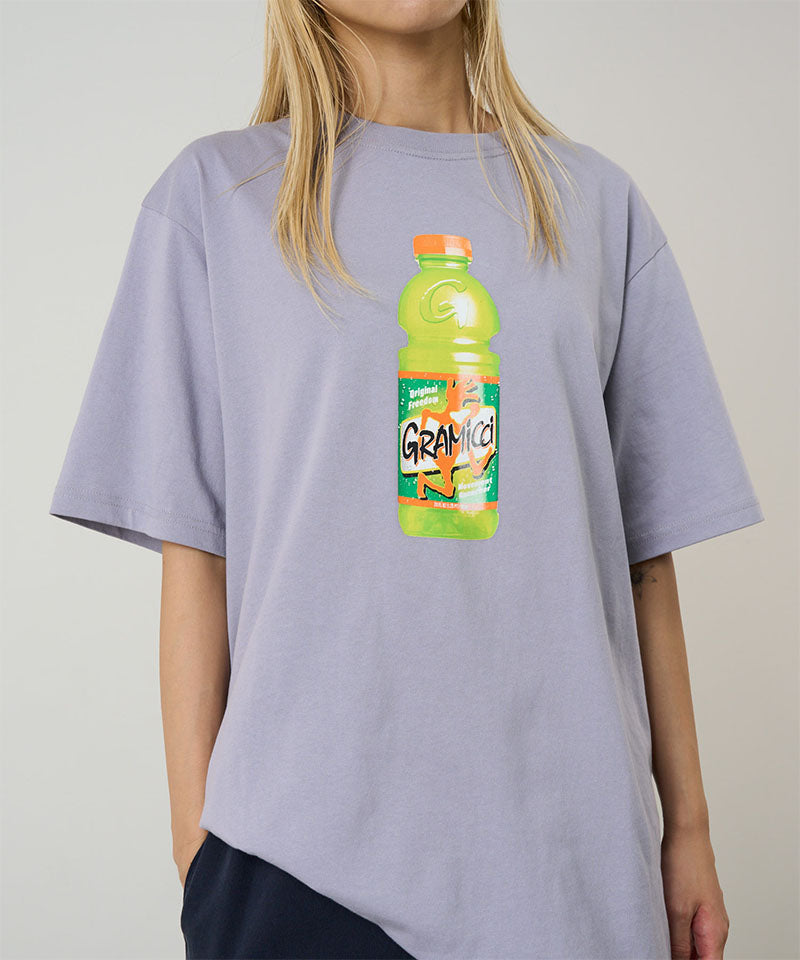 Model wearing a Gramicci lavender Quencher Tee with hydration drink graphic against a light tone background.