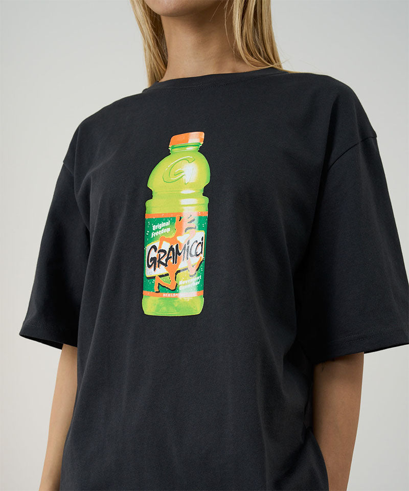 Model wearing a Gramicci vintage black Quencher Tee with hydration drink graphic against a light tone background.