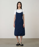 Model wearing a Gramicci Women's Woven Milton Dress in the color dark navy and a white undershirt on a light-tone background.
