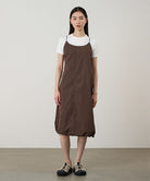 Model wearing a Gramicci Women's Woven Milton Dress in the color walnut and a white undershirt on a light-tone background.
