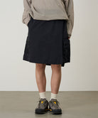 Model wearing black Gramicci Guide Skort and a beige jacket on a light-tone background.