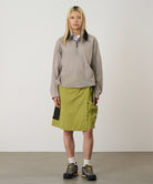 Model wearing field green Gramicci Guide Skort and a beige jacket on a light-tone background.