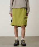 Model wearing field green Gramicci Guide Skort and a beige jacket on a light-tone background.
