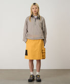 Model wearing mango colored Gramicci Guide Skort and a beige jacket on a light-tone background.