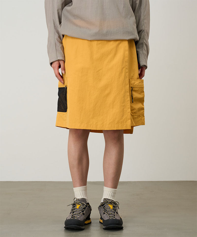 Model wearing mango colored Gramicci Guide Skort and a beige jacket on a light-tone background.