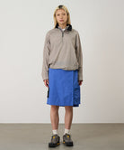 Model wearing blue Gramicci Guide Skort and a beige jacket on a light-tone background.