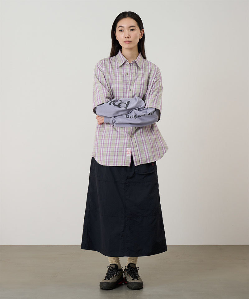 Person wearing a plaid shirt and black skirt against a plain background