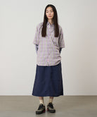 Person wearing a plaid shirt and navy skirt against a plain background