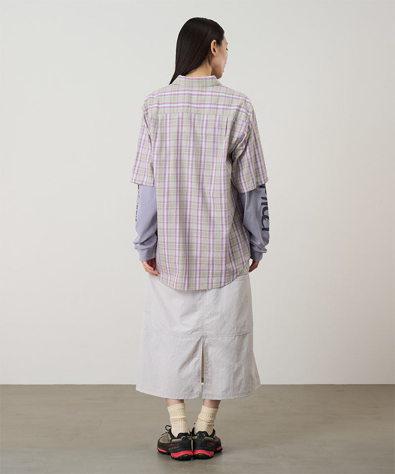 Person wearing a plaid shirt and white pants against a plain background