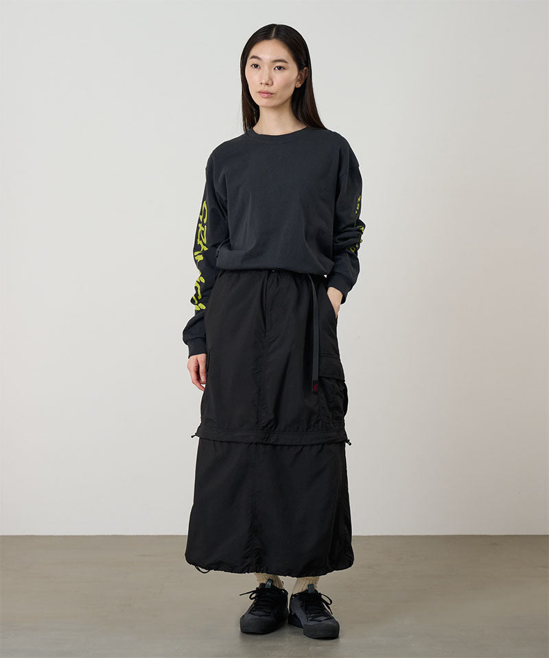 Model wearing a Gramicci Convertible Cargo Skirt in the color black and a black shirt on a light-tone background.