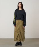 Model wearing a Gramicci Convertible Cargo Skirt in the color khaki and a black shirt on a light-tone background.