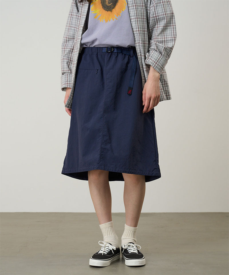 Person wearing a navy skirt with a plain background