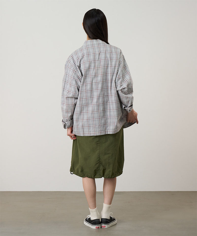 Person wearing a plaid shirt and green skirt against a plain background