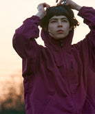 Woman wearing a pink Gramicci rain jacket with a blurred background