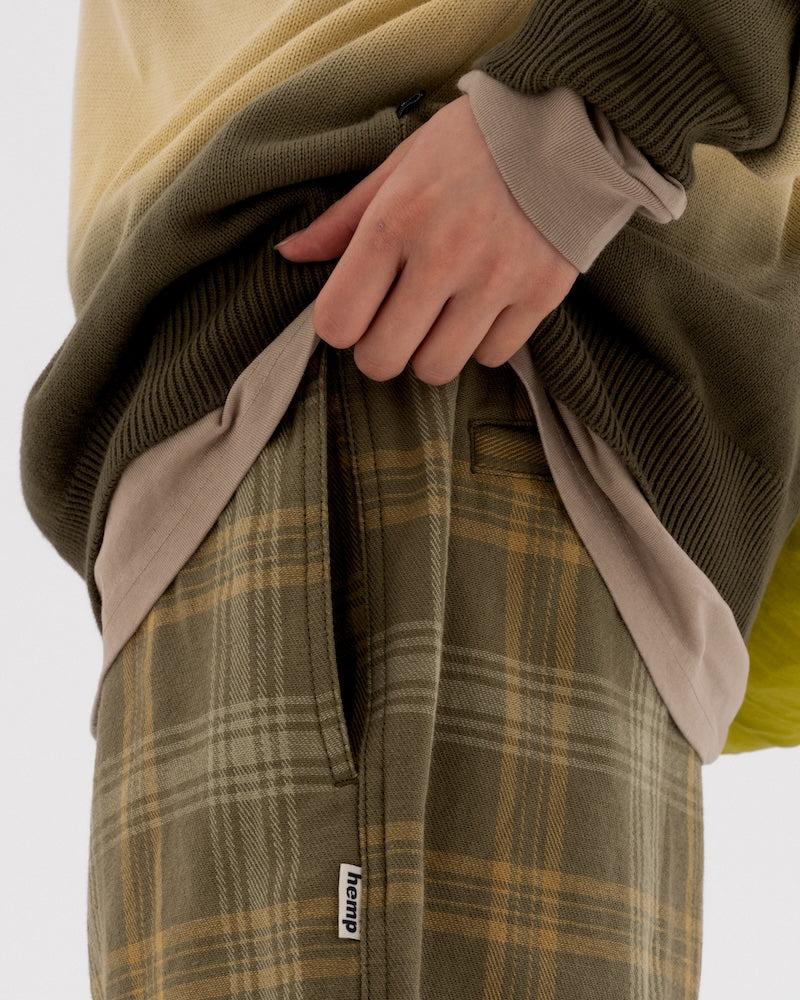 Model wearing plaid Gramicci hemp pants on a light-tone background.