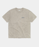 A light beige mineral-wash short-sleeve t-shirt with a small dark blue 'GRAMICCI' graphic on the left chest, displayed flat against a solid white background.